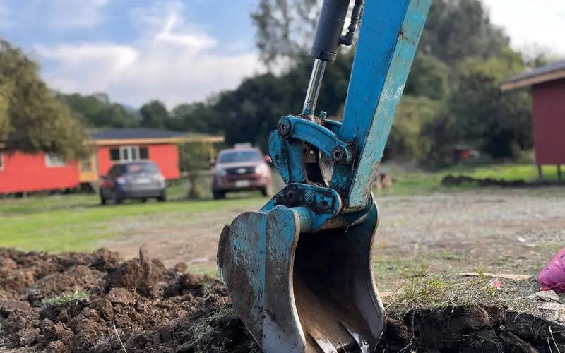 Balde de miniexcavadora removiendo tierra durante una obra en terreno